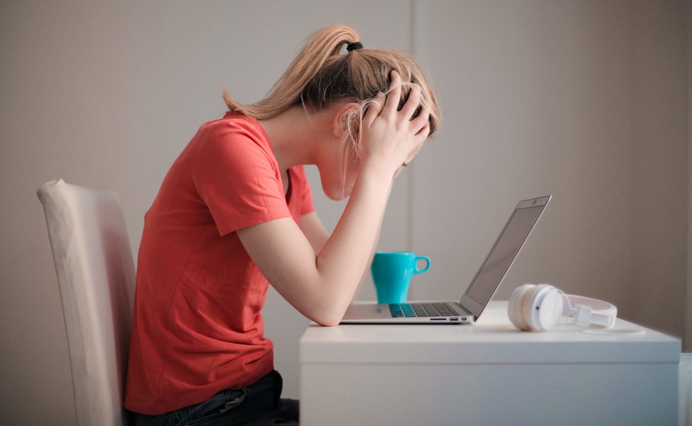 Seorang perempuan merasa murung di depan laptop.